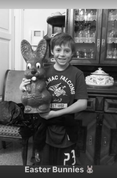 Black and white photo of a boy holding a large chocolate Easter bunny.