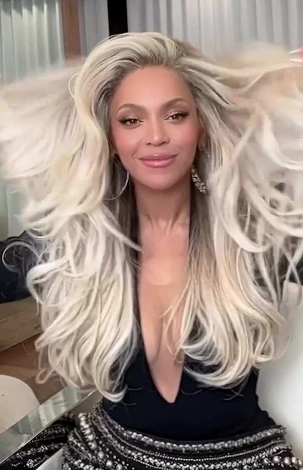Beyoncé with long, blonde hair, wearing a black, low-cut top.