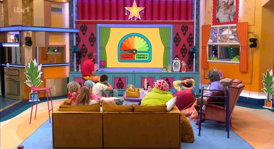 Housemates watching a family task results on a large screen.