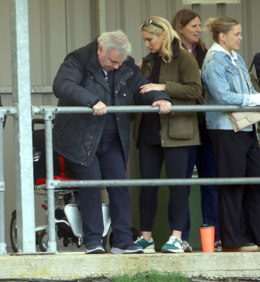 A man and woman standing behind a railing at a sporting event.