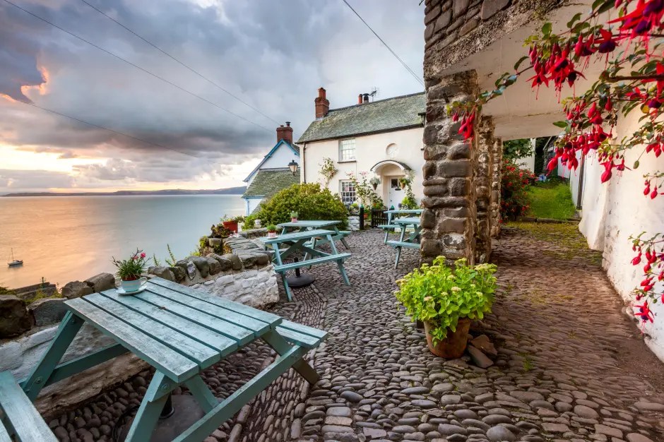 Cobblestone patio with picnic tables overlooking the sea at sunset.
