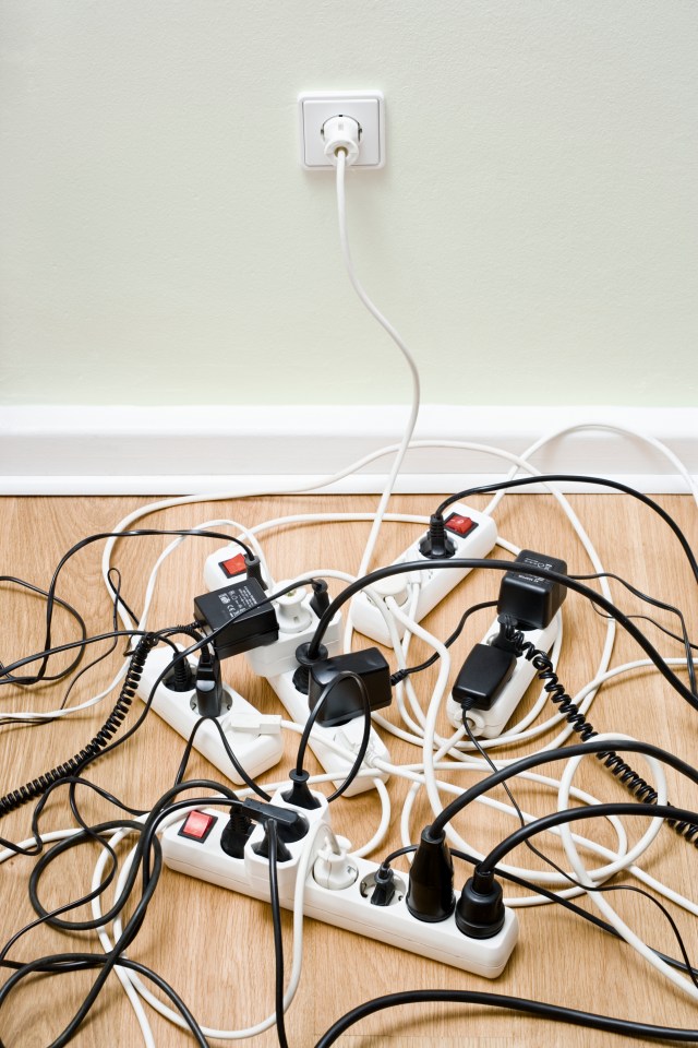 Tangled power cords and surge protectors on the floor.