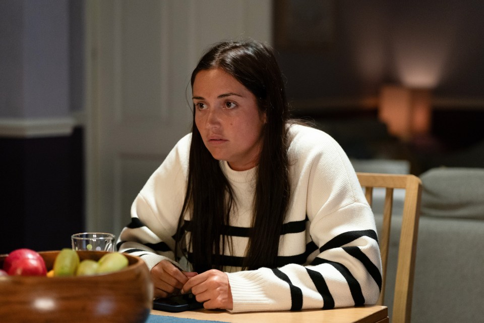 Lauren Branning from EastEnders sits at a table.
