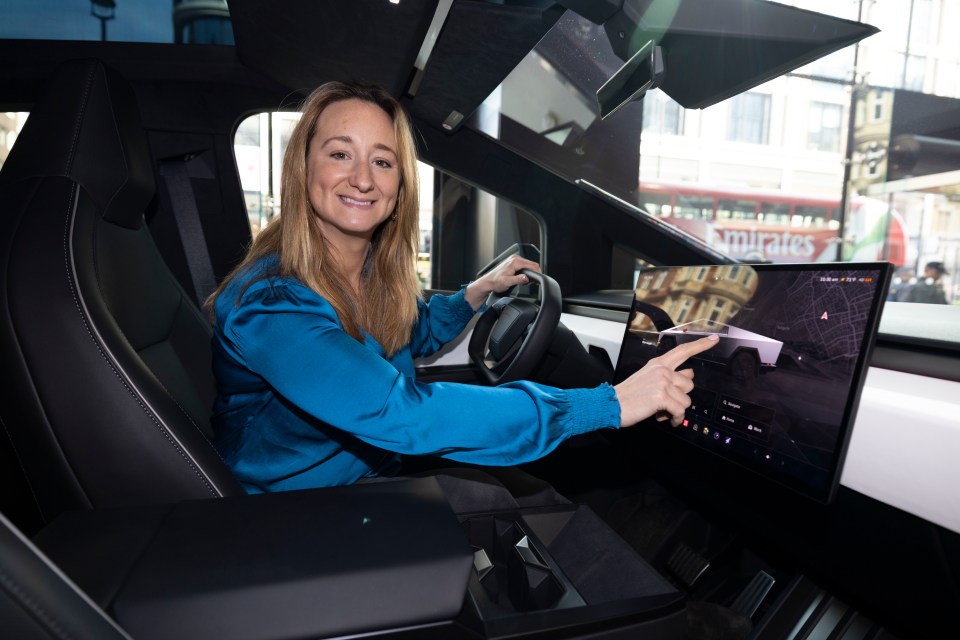 Woman in a blue shirt sitting in a Tesla Cybertruck and using the touchscreen.