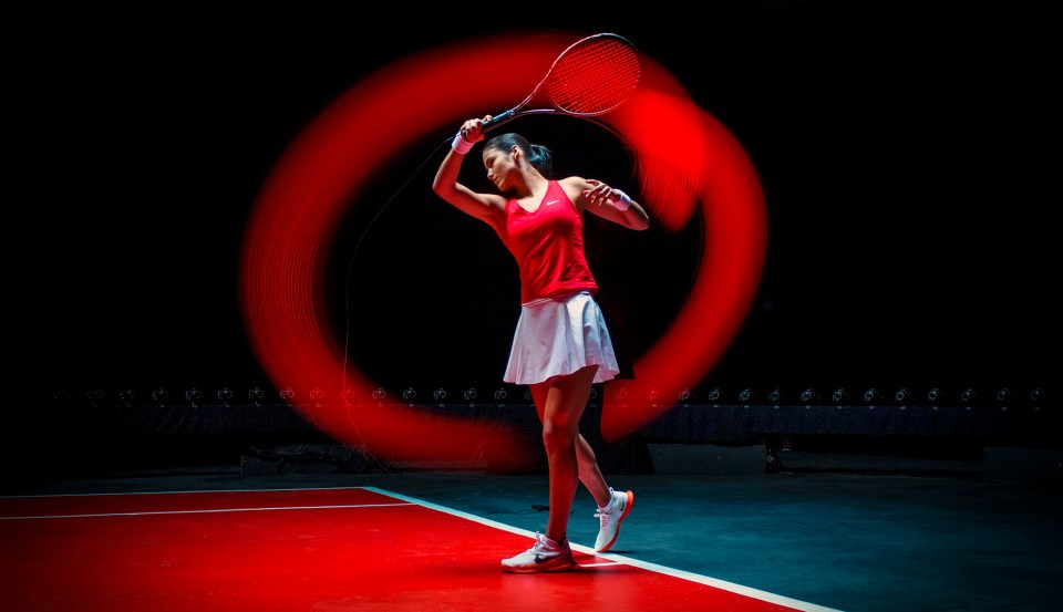 Emma Raducanu playing tennis with a red light trail behind her racket.