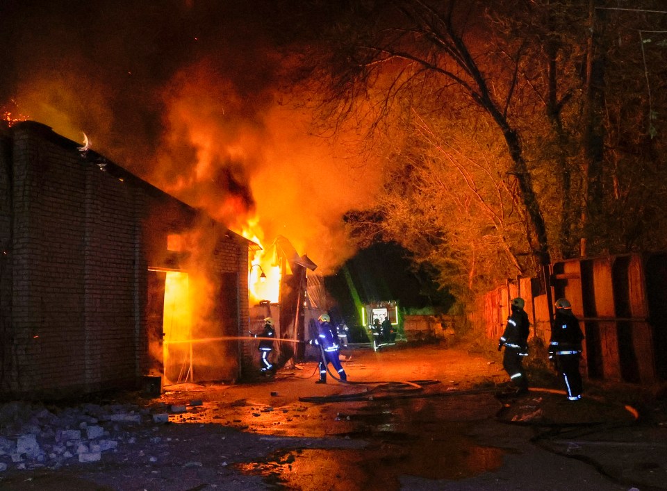Firefighters battling a large fire at night.