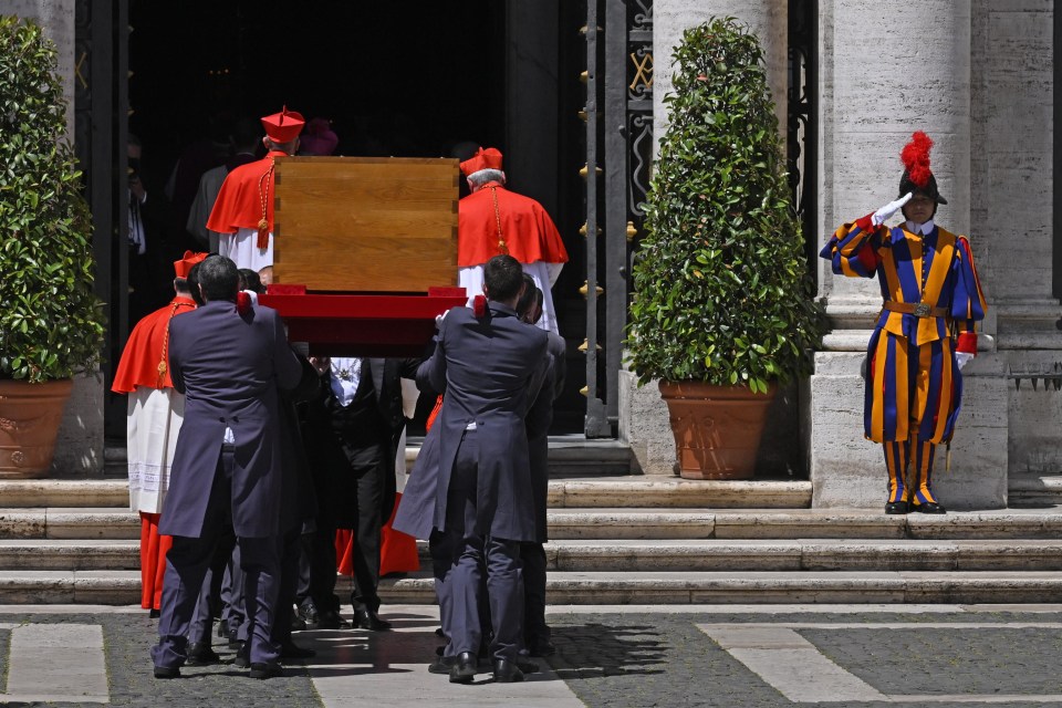 Men in suits carrying a wooden casket.