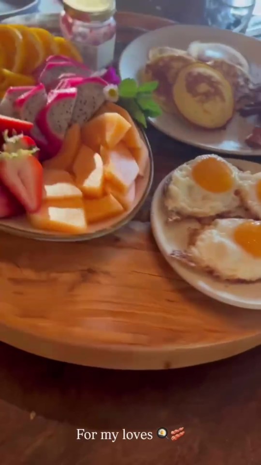 Breakfast platter with fruit, pancakes, and fried eggs.