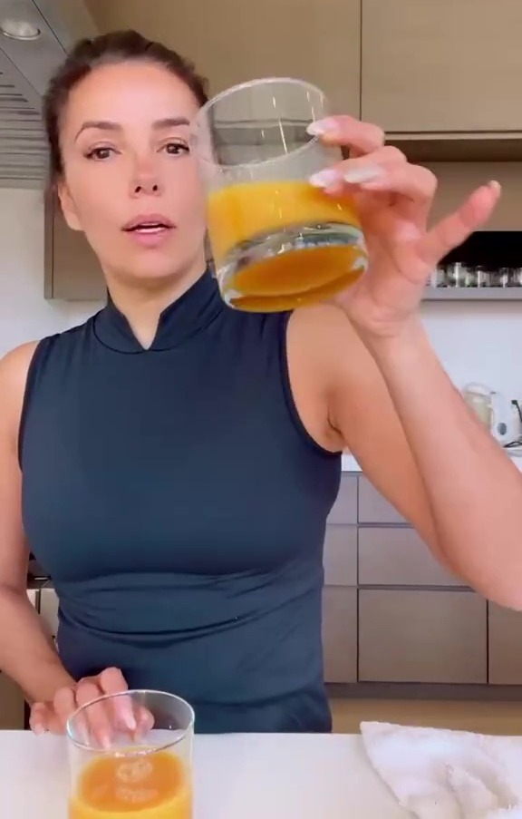 Eva Longoria holding a glass of orange juice.