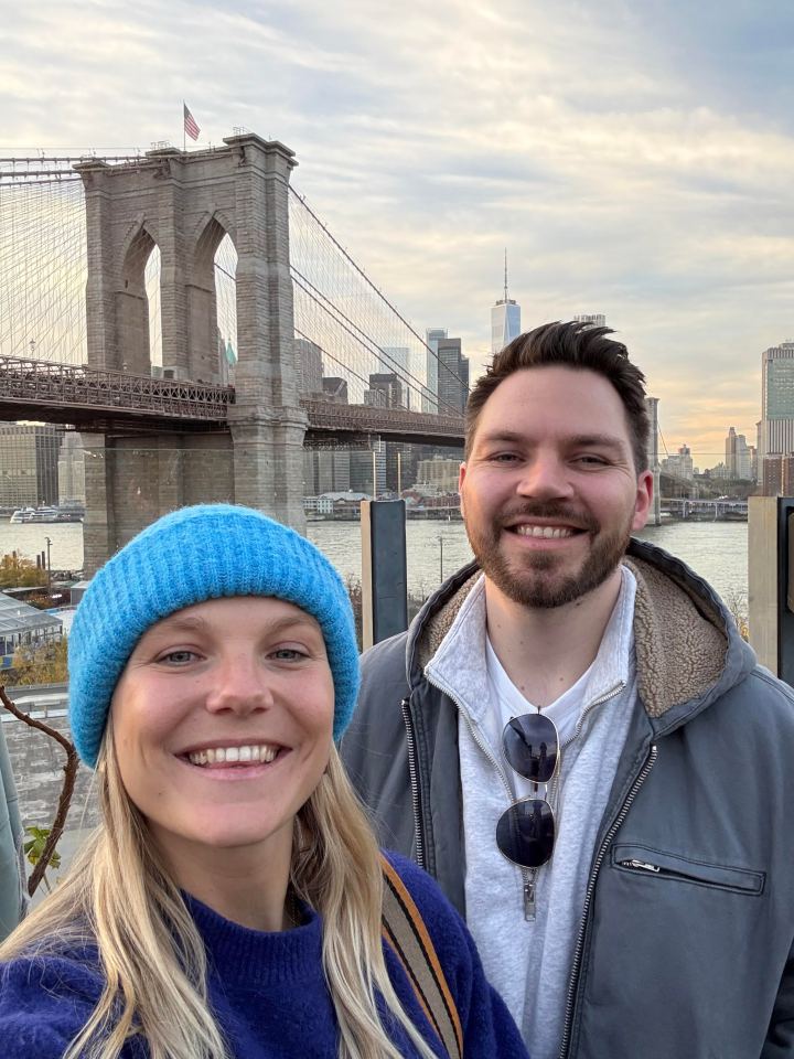 Couple posing in front of the Brooklyn Bridge in New York City.