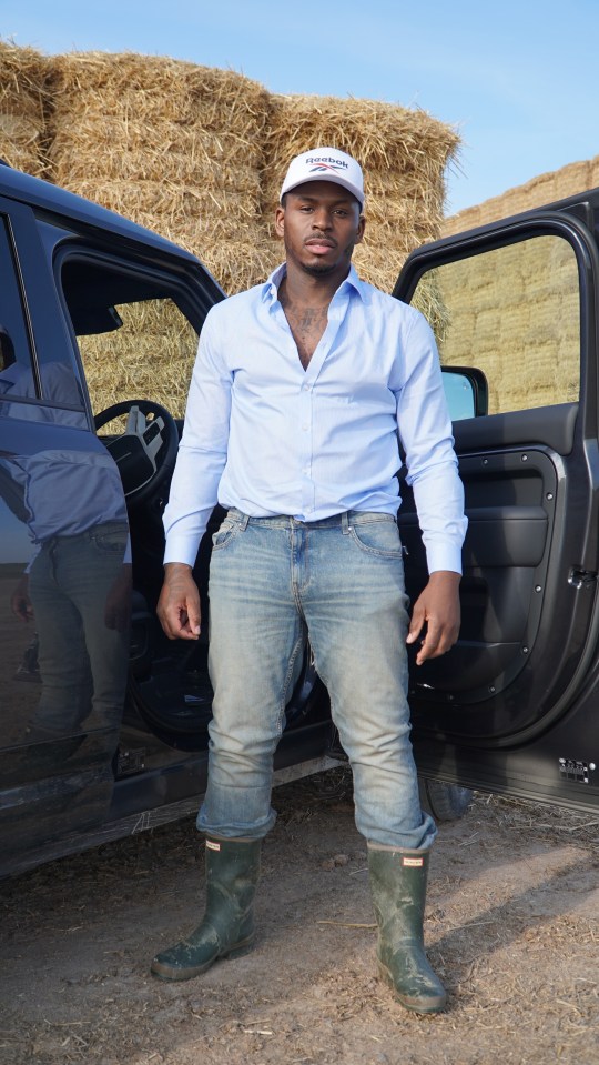 Man standing by a car in a field.