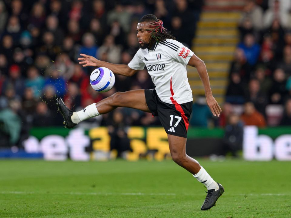 Alex Iwobi of Fulham kicking a soccer ball during a Premier League match.