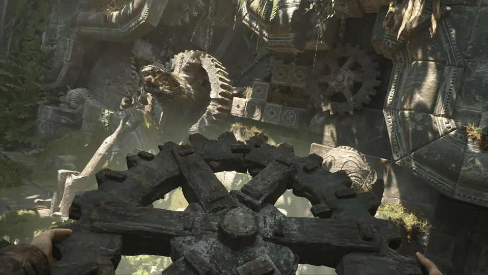 Gameplay screenshot showing a large, weathered gear mechanism in overgrown ruins.