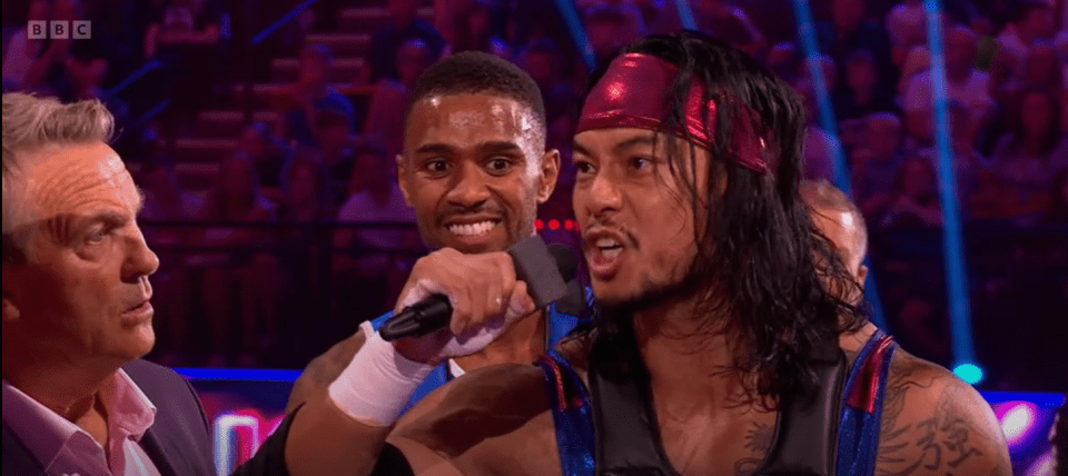 Two men being interviewed, one holding a microphone.