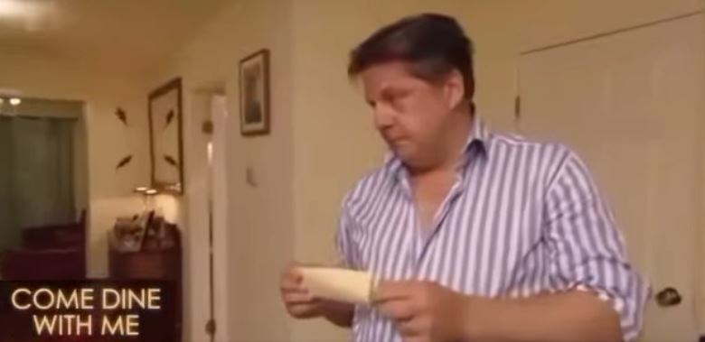 Screenshot from Come Dine With Me showing a man holding a piece of paper.
