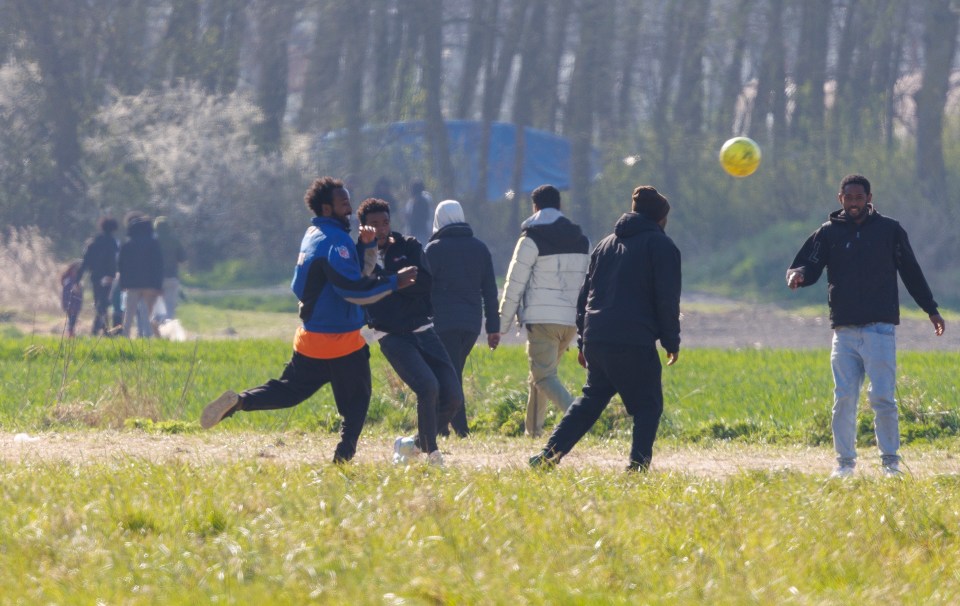 Migrants playing soccer in a field.