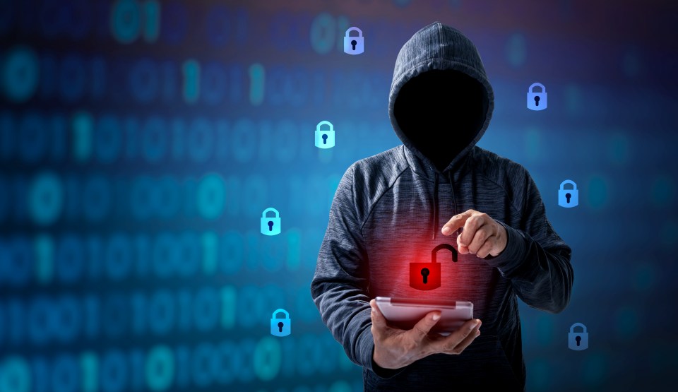 A hooded figure using a tablet to unlock a digital lock.