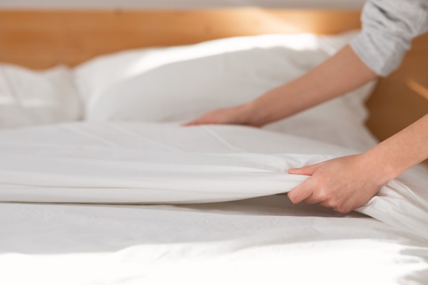 Hands making a bed.