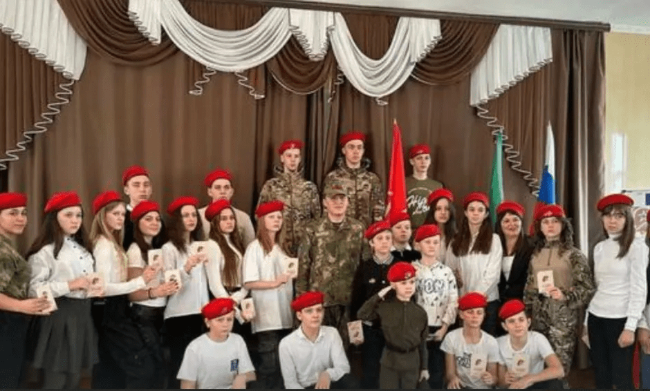Group photo of children and adults wearing red berets.