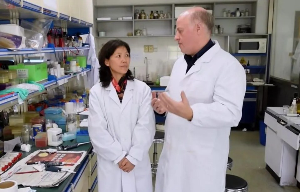 Two scientists in lab coats conversing in a laboratory.