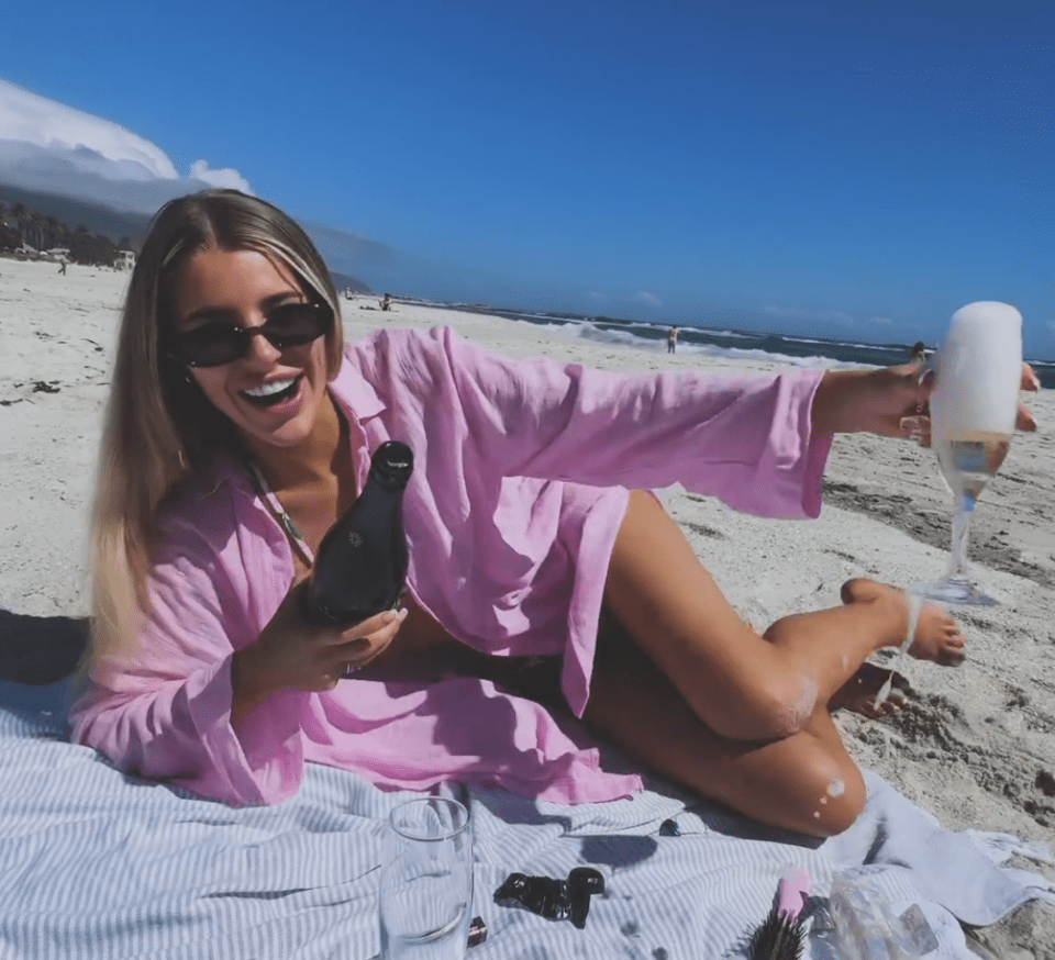 Woman on beach pouring champagne.