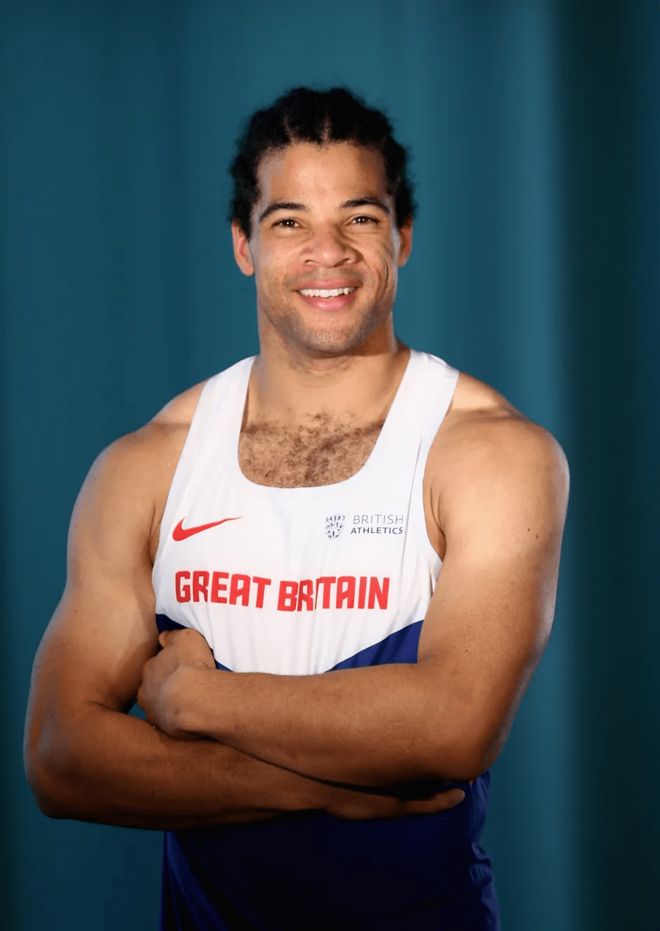 Portrait of a smiling man wearing a Great Britain athletics singlet.