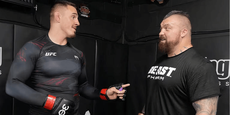 Two men talking, one in a UFC shirt and the other in a Beast Pharm shirt.