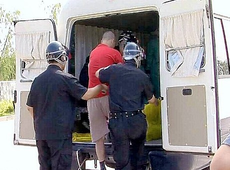 Two men in custody being escorted into a van.