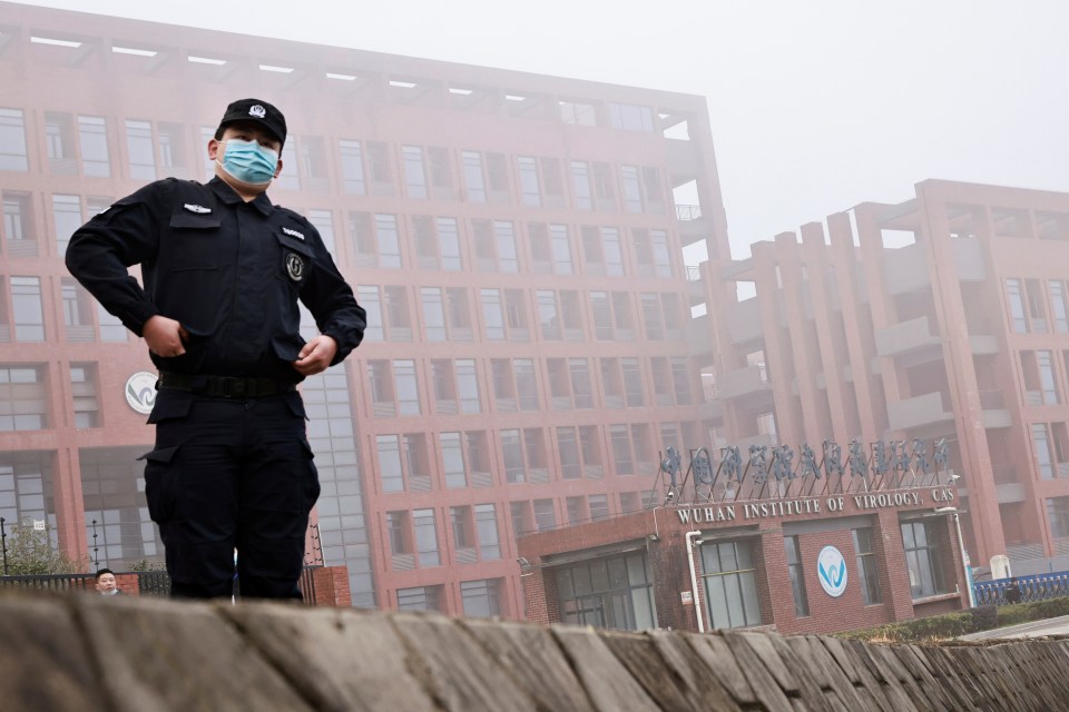 Security guard in face mask standing in front of the Wuhan Institute of Virology.