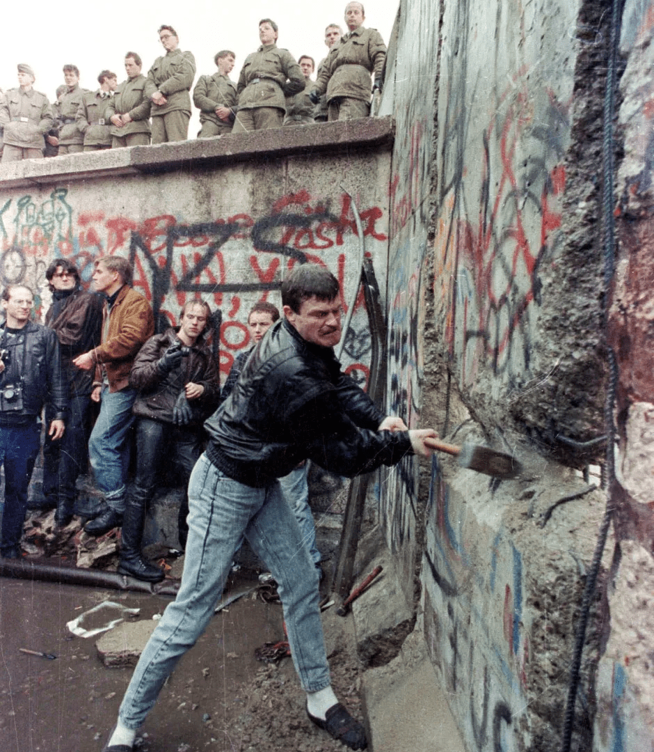 A man using a sledgehammer to break down the Berlin Wall.