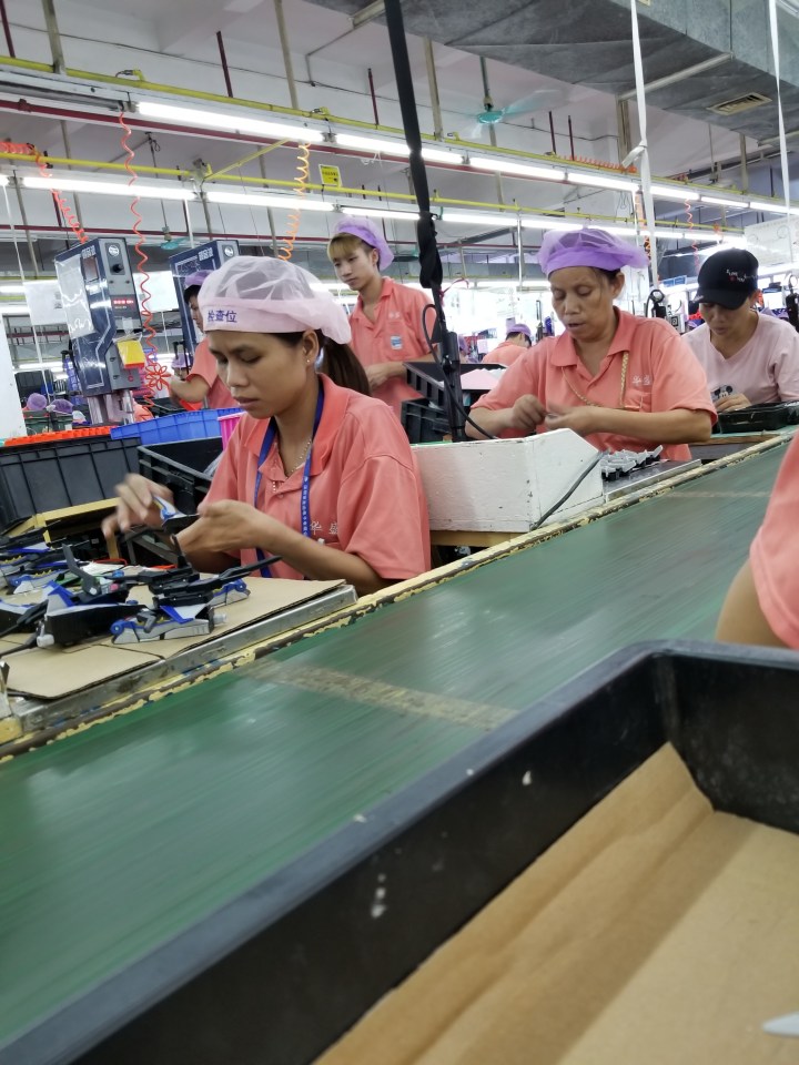 Workers assembling toys on a factory assembly line.
