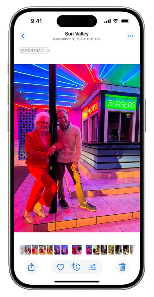 iPhone photo of two people posing in front of a brightly lit diner.