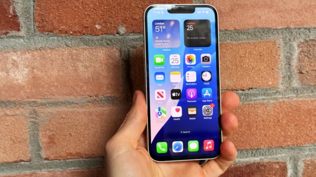 Hand holding iPhone displaying home screen.