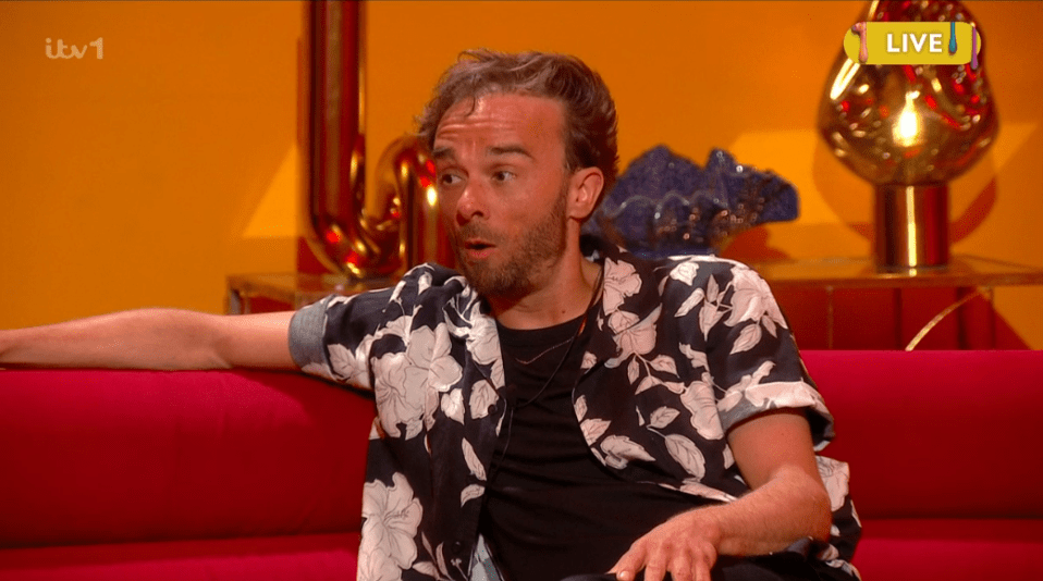 Man in floral shirt on a red couch.