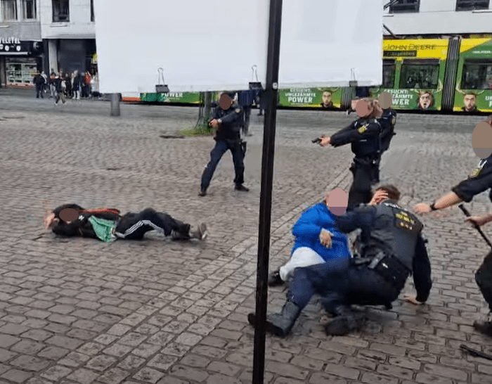 Police officers apprehending a suspect on the ground.