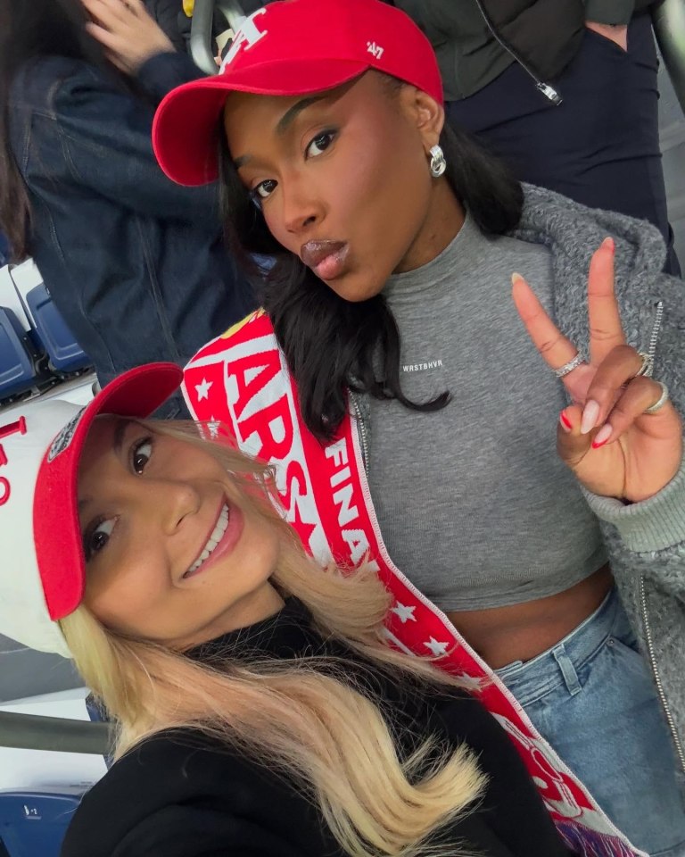 Two women wearing baseball caps and smiling for a selfie.