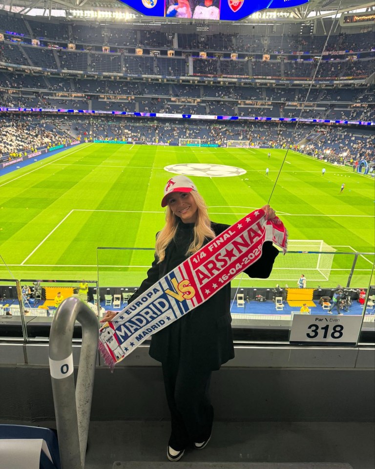Woman at a soccer game holding Arsenal scarf.