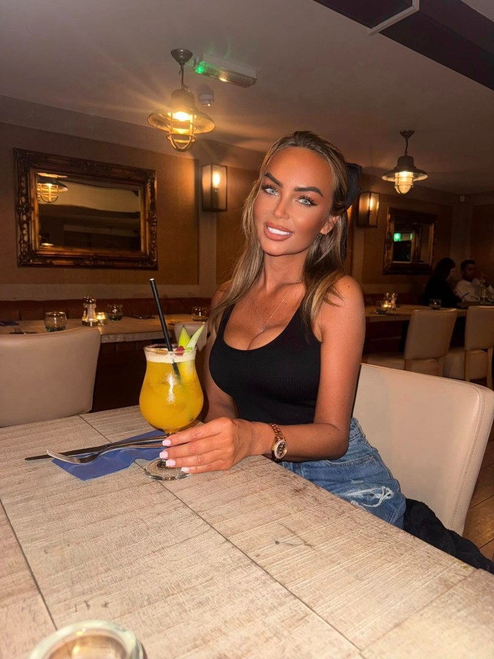 Woman sitting at a restaurant table with a cocktail.