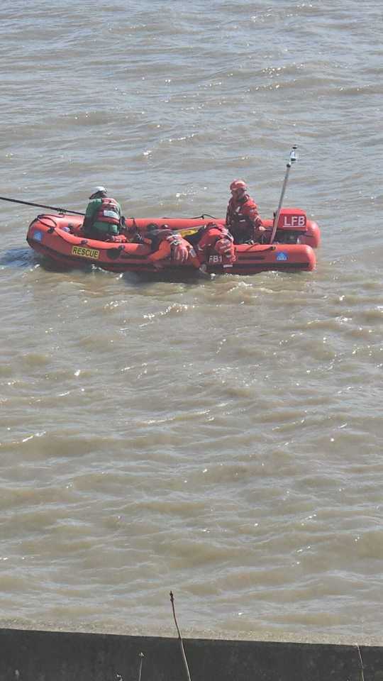 Emergency responders on a London riverbank during a search.