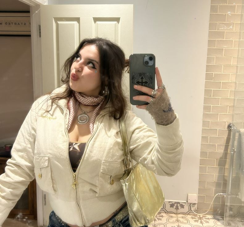 A young woman takes a selfie in a bathroom mirror.