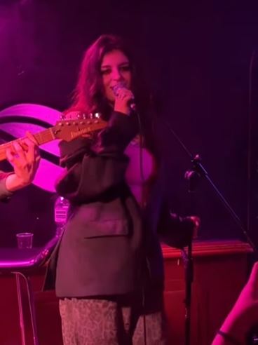 A woman singing and playing guitar on stage.