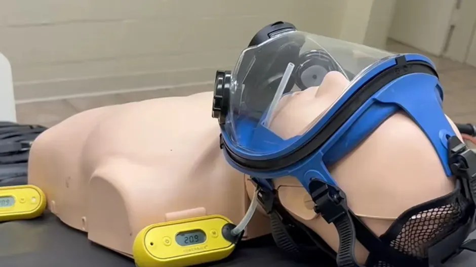 Medical training mannequin with a blue oxygen mask.