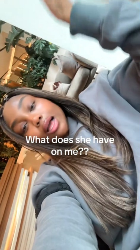 A woman in a light gray hoodie asks, "What does she have on me?"