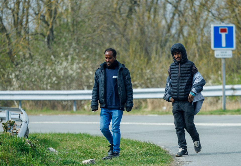 Two migrants walking on a road.