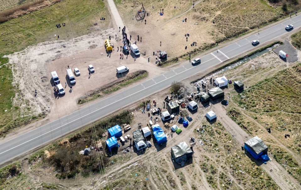 Aerial view of migrant camp with tents and vehicles.
