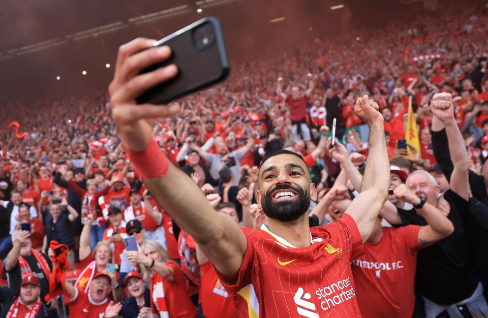 Mohamed Salah taking a selfie with celebrating Liverpool fans.