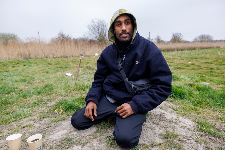 A man sits on the ground outdoors.