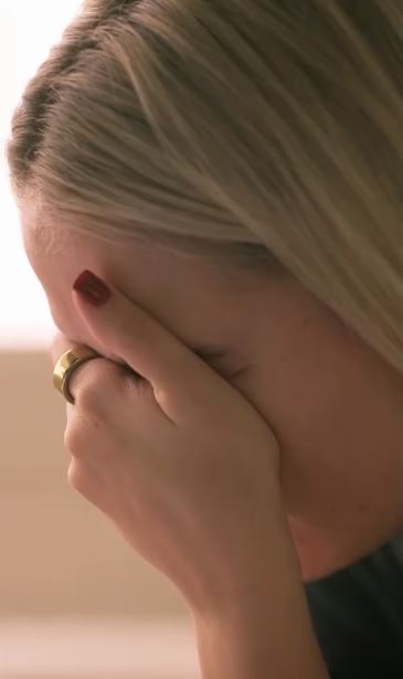 Woman with blonde hair covering her face with her hand.
