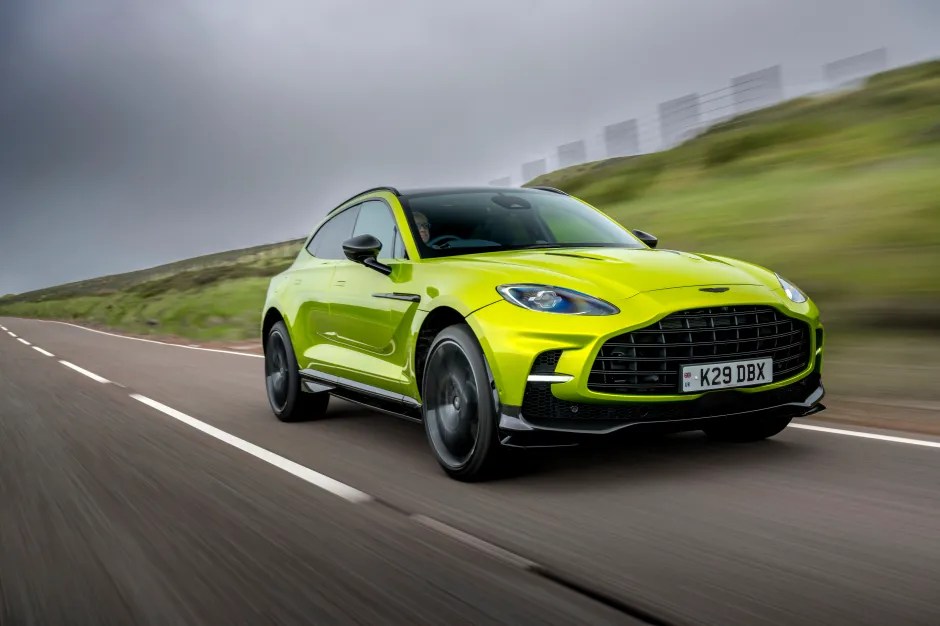 Lime green Aston Martin DBX driving on a road.