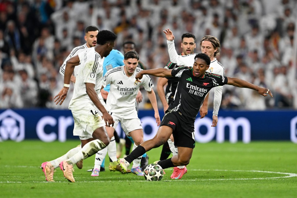 Myles Lewis-Skelly of Arsenal challenged by Real Madrid players during a soccer match.